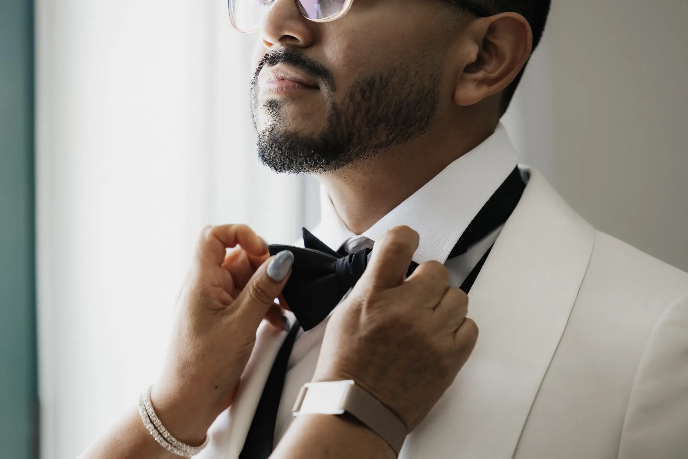 Groom adjusting his black bow tie before the ceremony