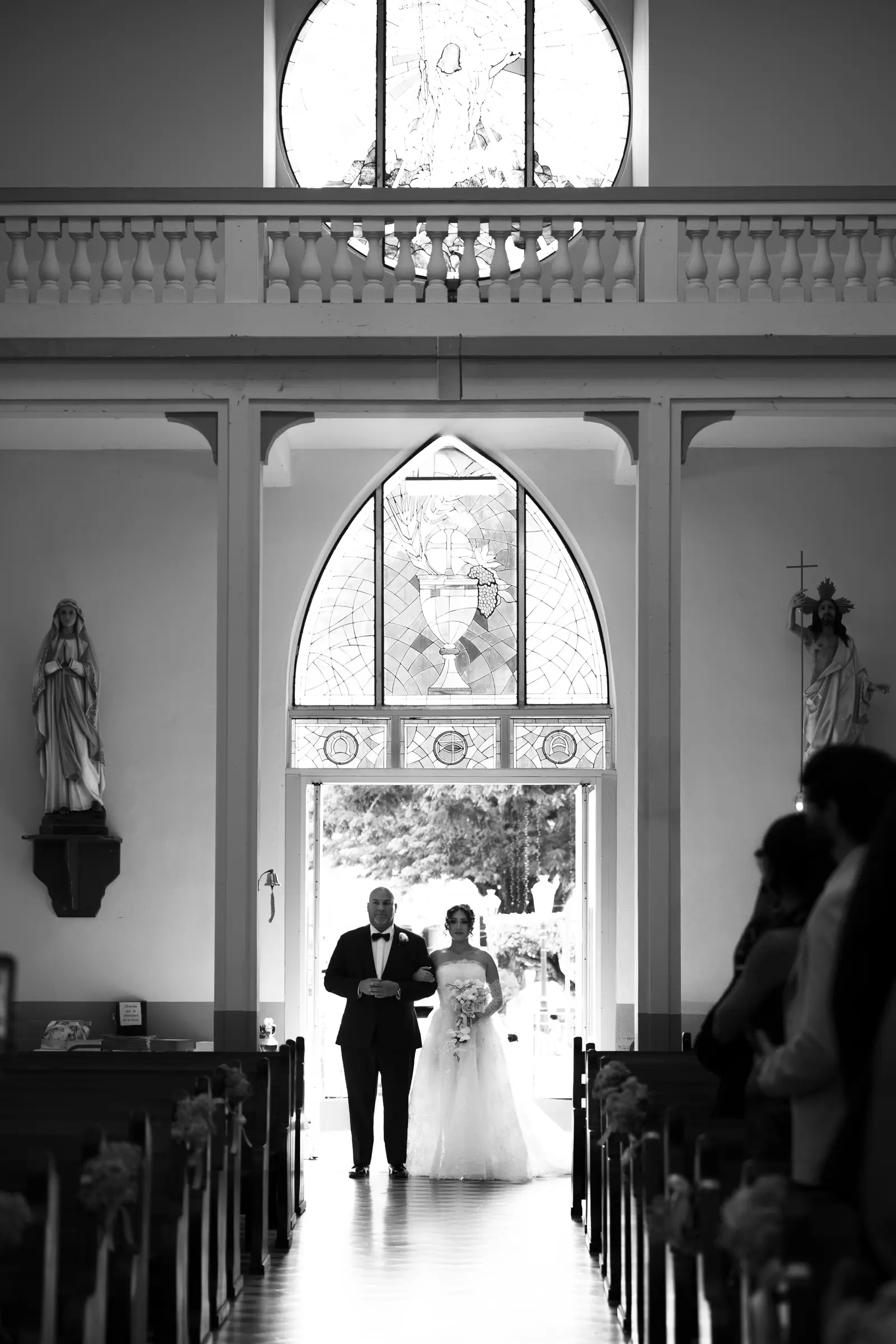 Bride entering a Puerto Rico church on her father's arm beneath a Gothic stained-glass window