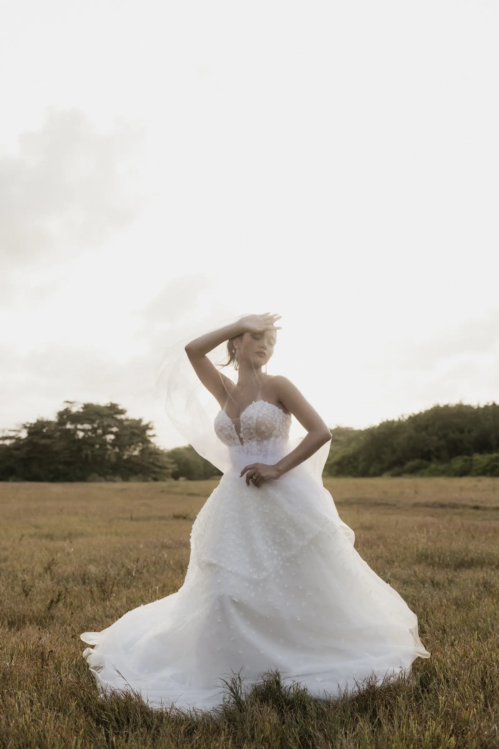 Bride walking through an open field in her wedding dress