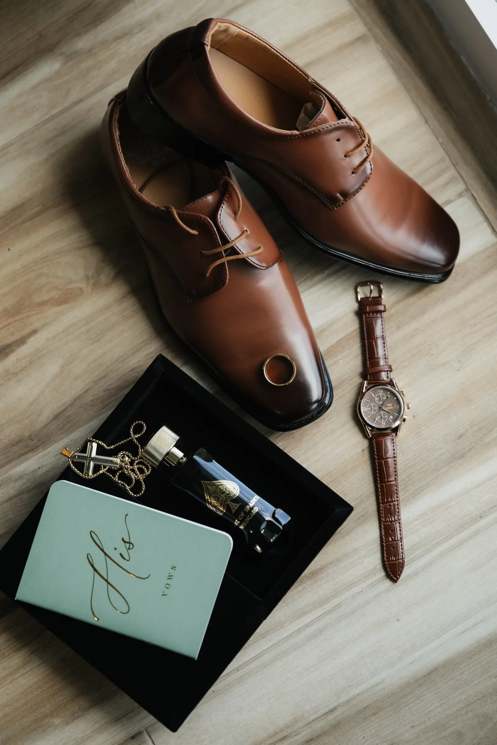 Groom's leather shoes, watch, and cufflinks arranged for a flat lay