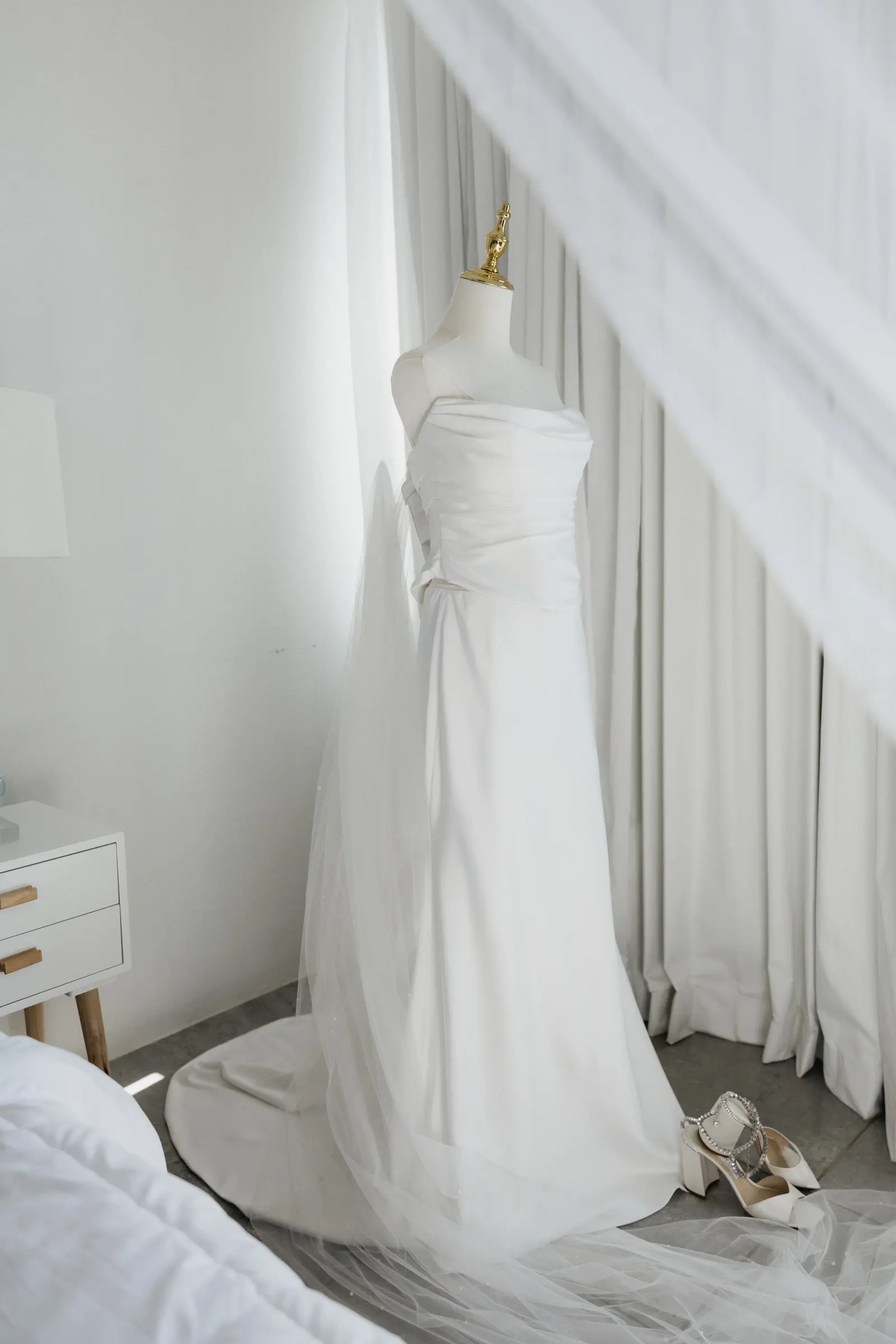 Wedding dress hanging by a window before the ceremony