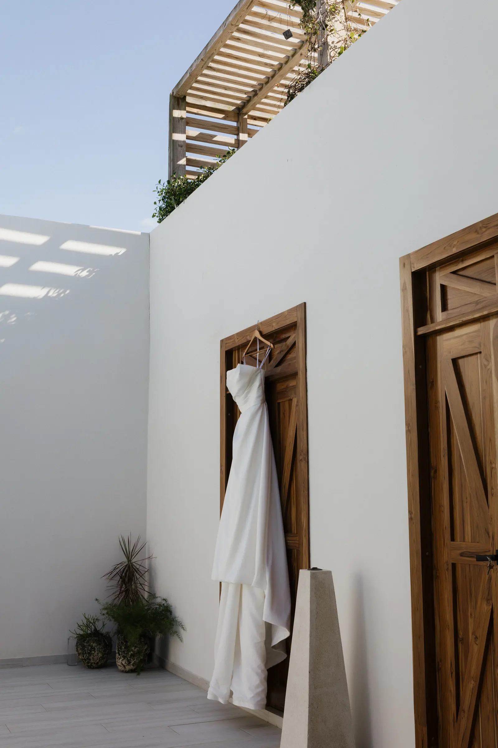 Wedding gown hanging on a door framed by tropical greenery