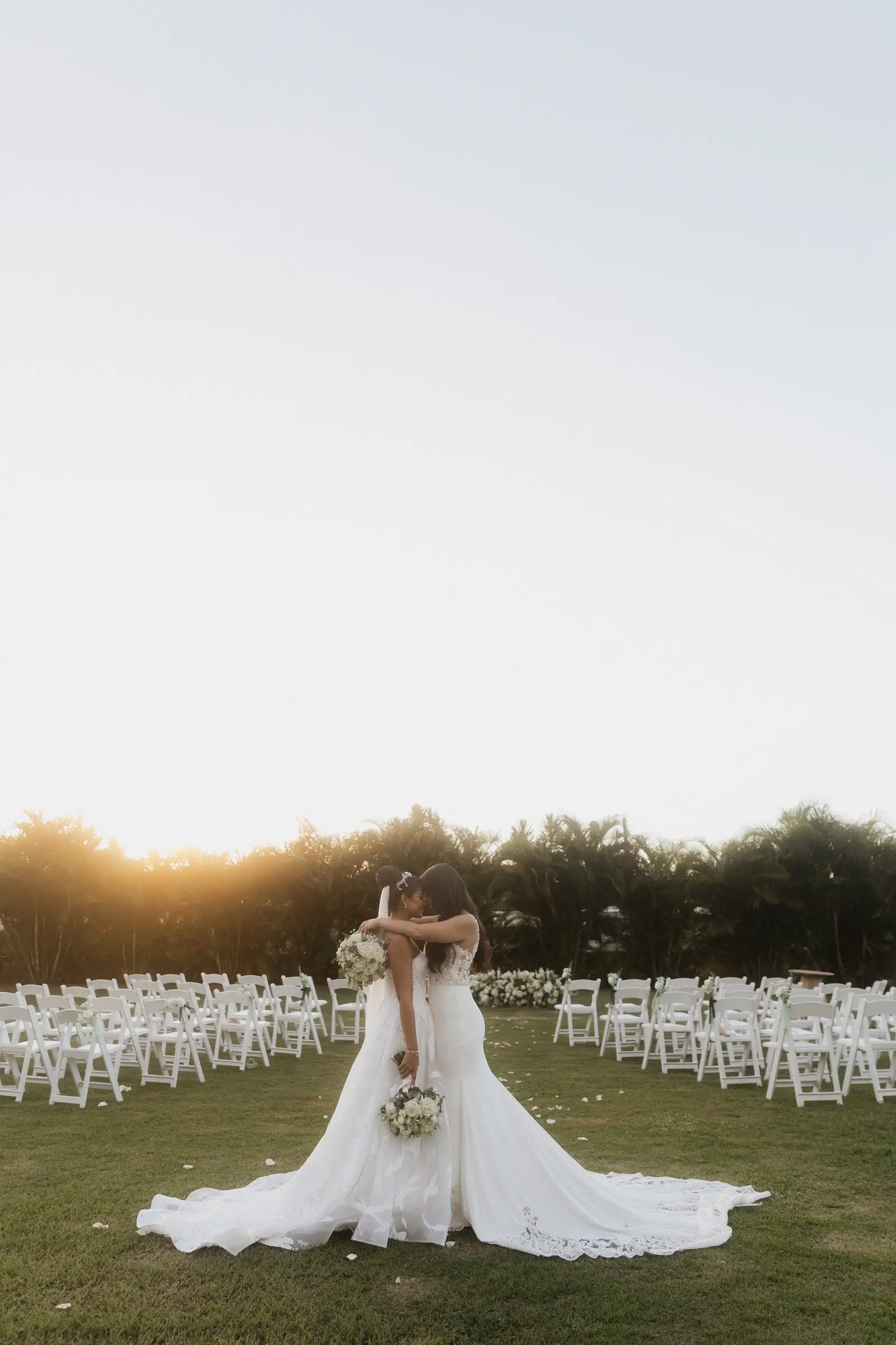 Bride's dress train spread out during an outdoor ceremony at sunset