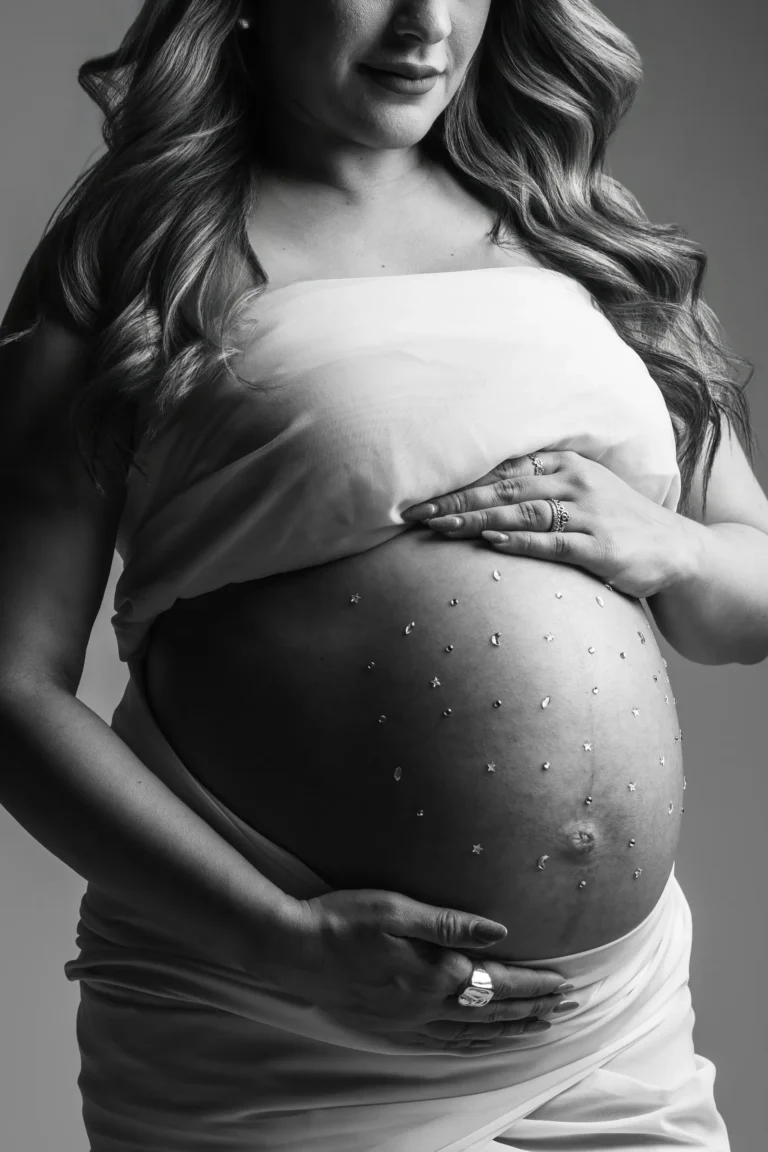 Black and white close-up of a pregnant belly cradled by two hands