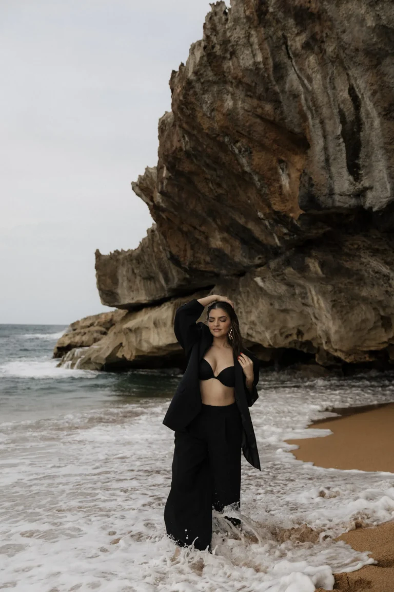 Woman in a black outfit posed against a dramatic rock formation