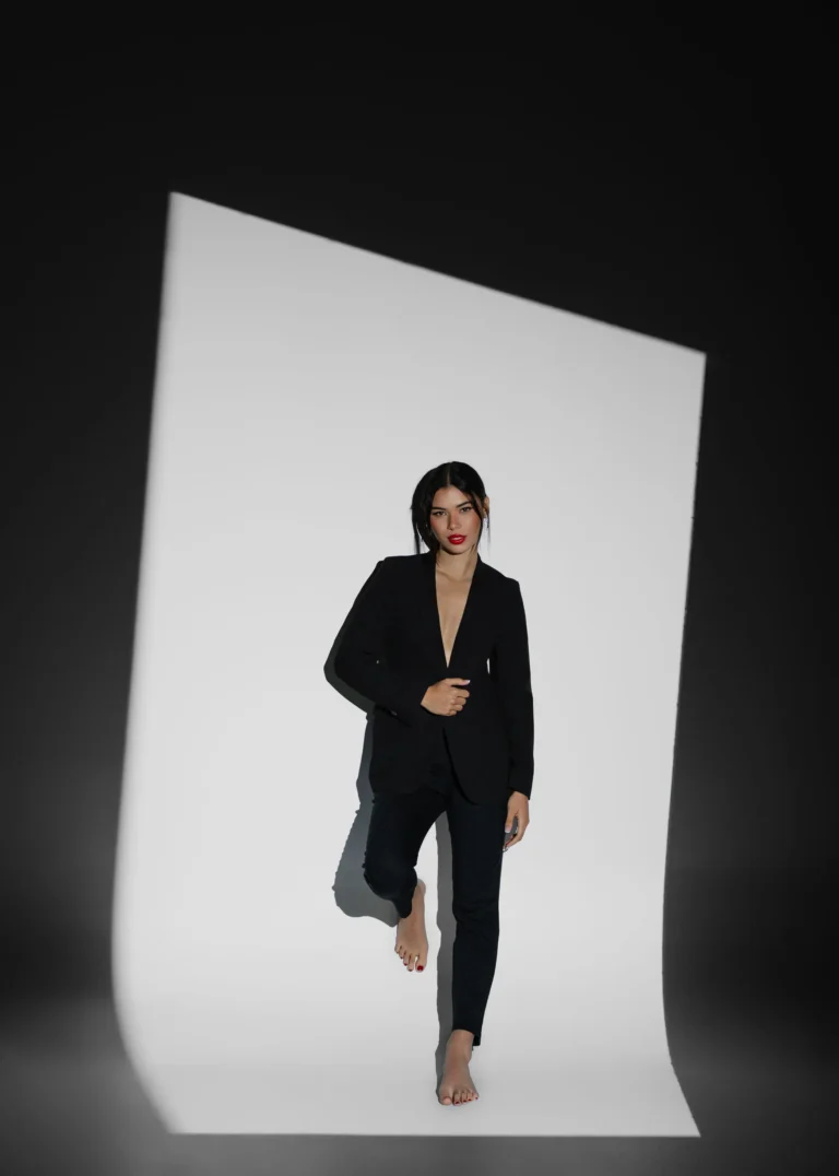 Woman in a black suit standing in front of a folded white paper backdrop