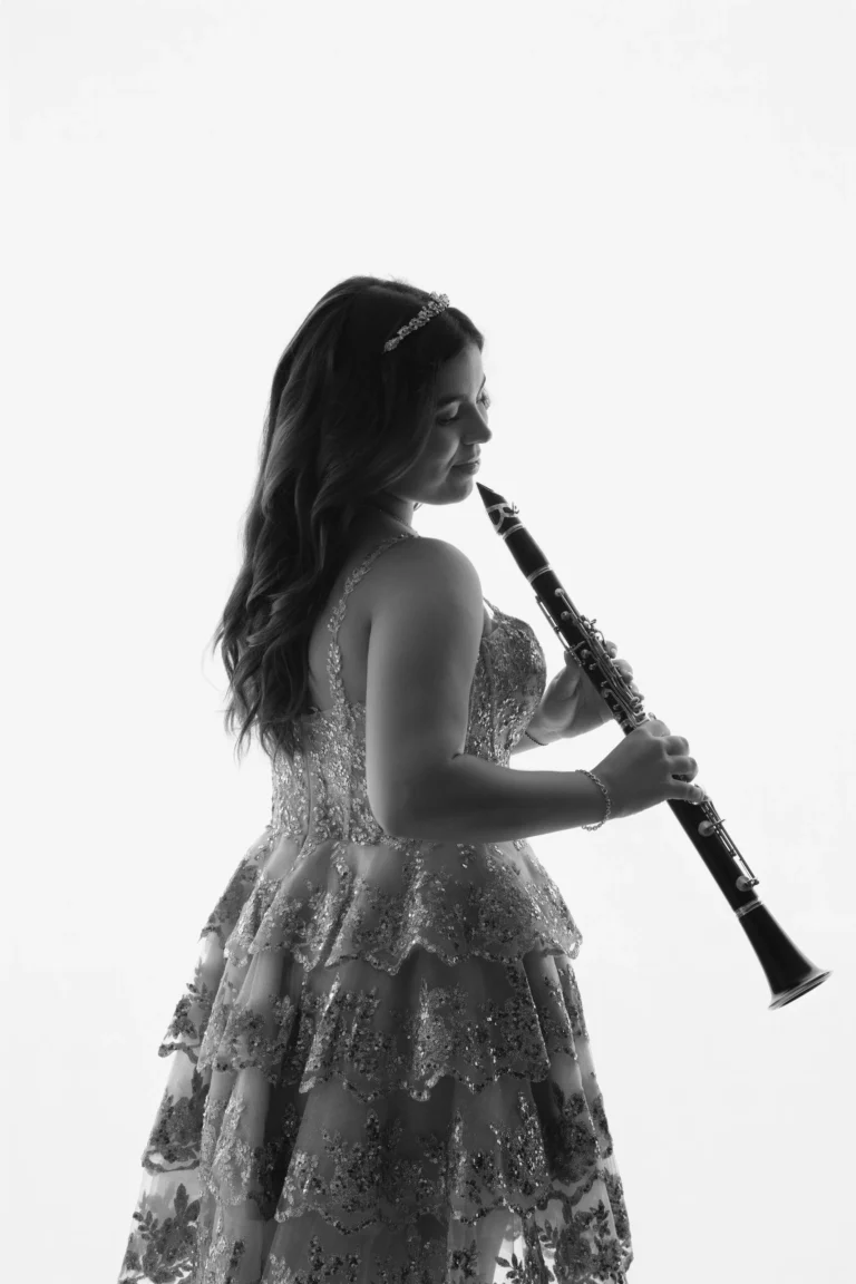 Black-and-white portrait of a woman in a lace gown holding a clarinet