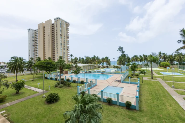 Aerial view of a high-rise condominium tower with a pool and landscaped grounds