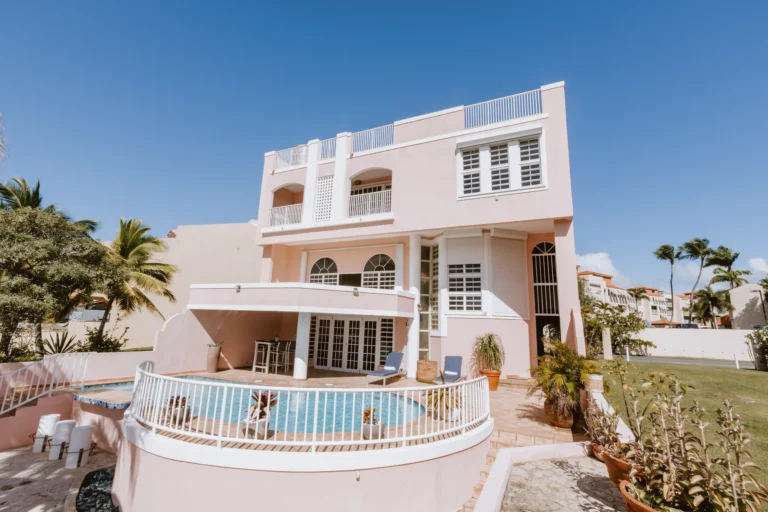 Pink multi-story oceanview home exterior with a pool terrace and palm trees