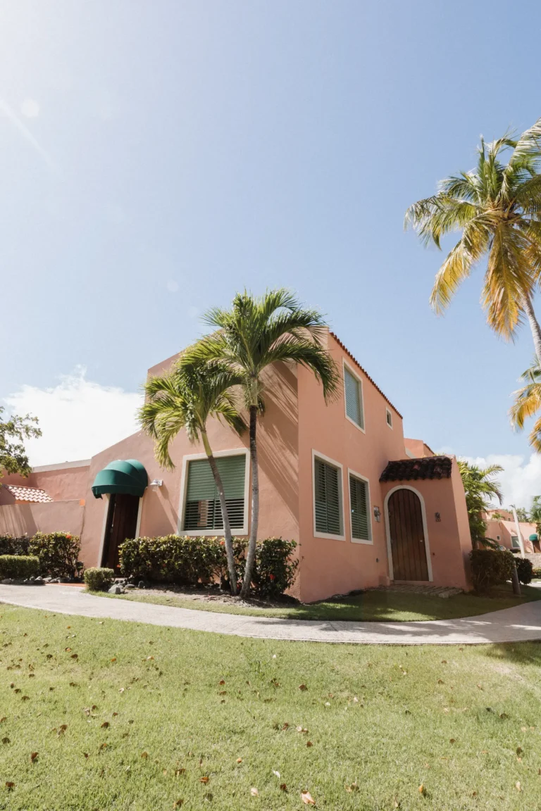 Pink two-story home exterior with a palm tree and manicured lawn